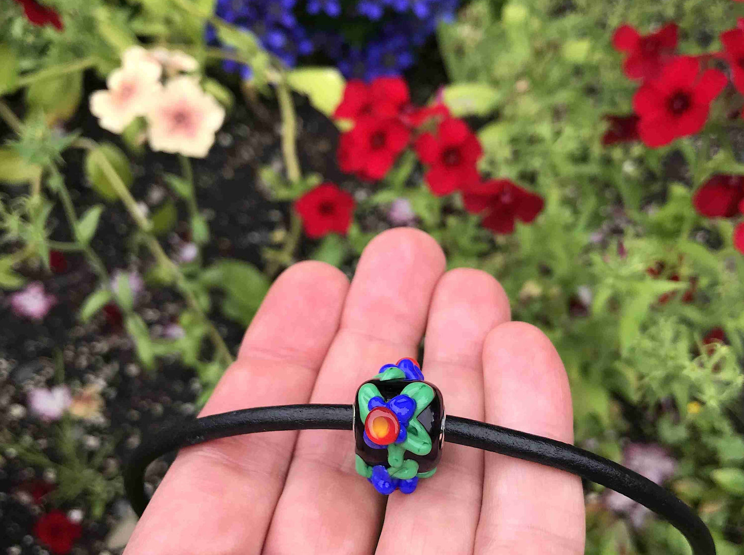 Choker necklace with black cylinder glass bead (Murano-style glass handmade in Montreal), 3-dimensional red-blue-green flowers, black leather cord, stainless steel clasp