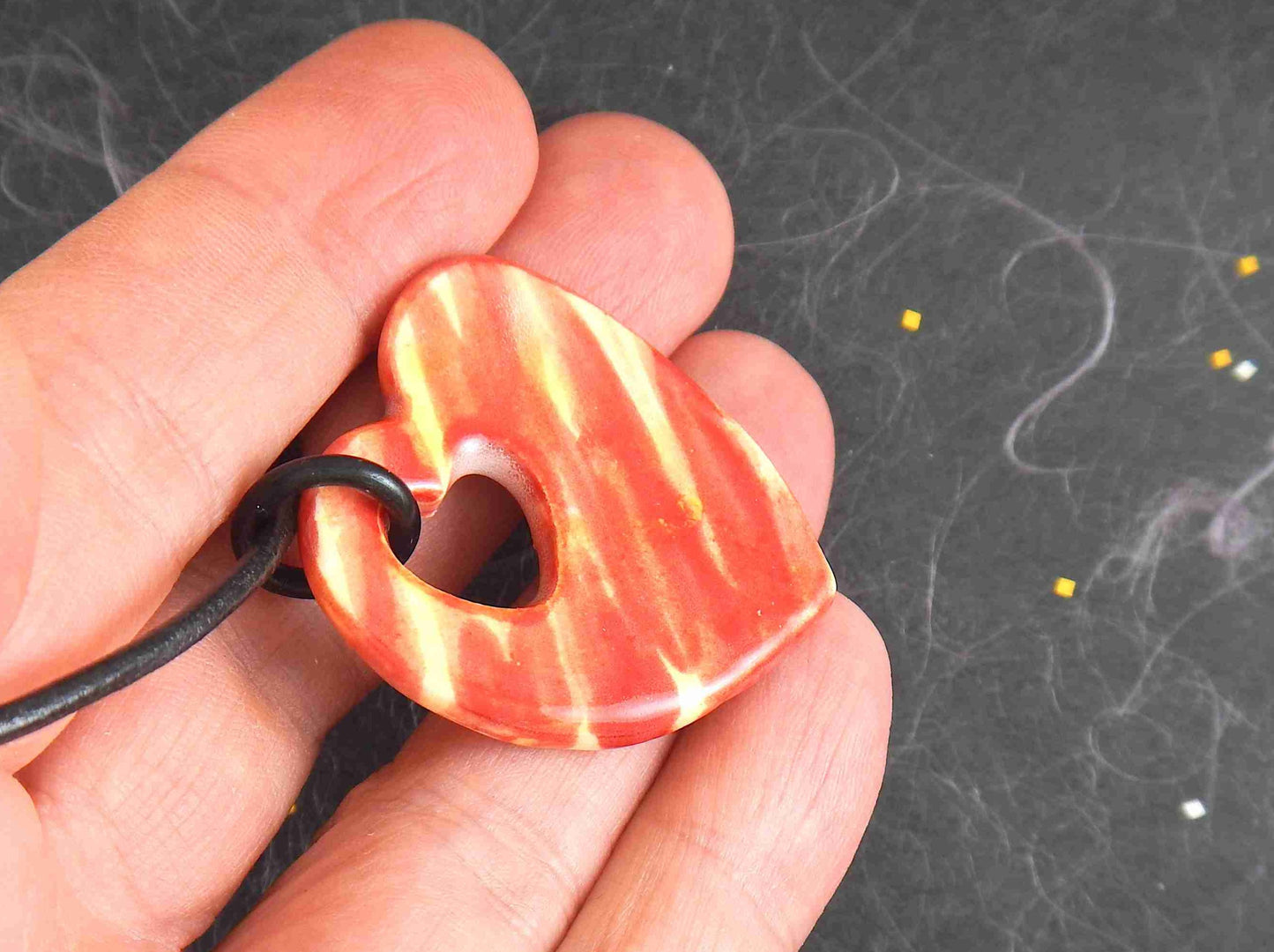 18-inch necklace with marbled red and yellow ceramic heart handmade in Montreal, heart-shaped hole, black leather cord, stainless steel clasp