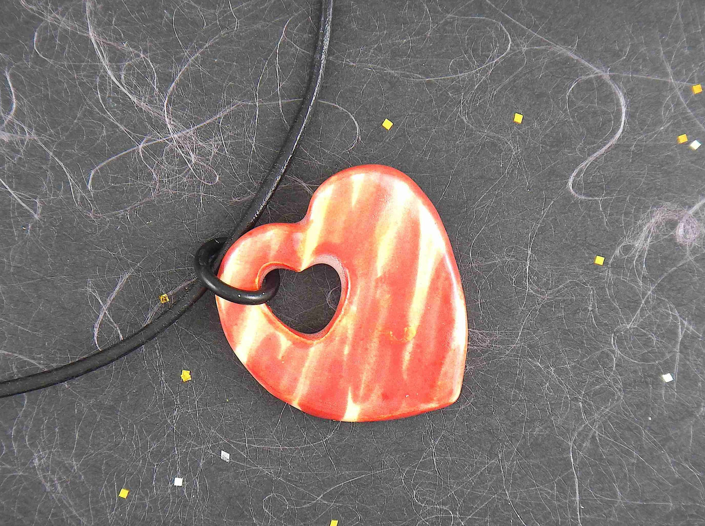 18-inch necklace with marbled red and yellow ceramic heart handmade in Montreal, heart-shaped hole, black leather cord, stainless steel clasp