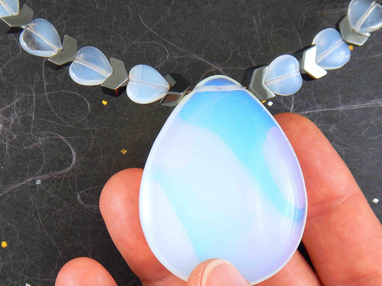 Collier tour de cou avec pendentif goutte 50mm de pierre de lune synthétique (opalite), petits coeurs et chevrons en hématite, fermoir métal