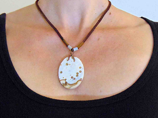 17-inch necklace with matte white and caramel jasper pendant on brown leather cord, antique glass cylinder beads, copper clasp