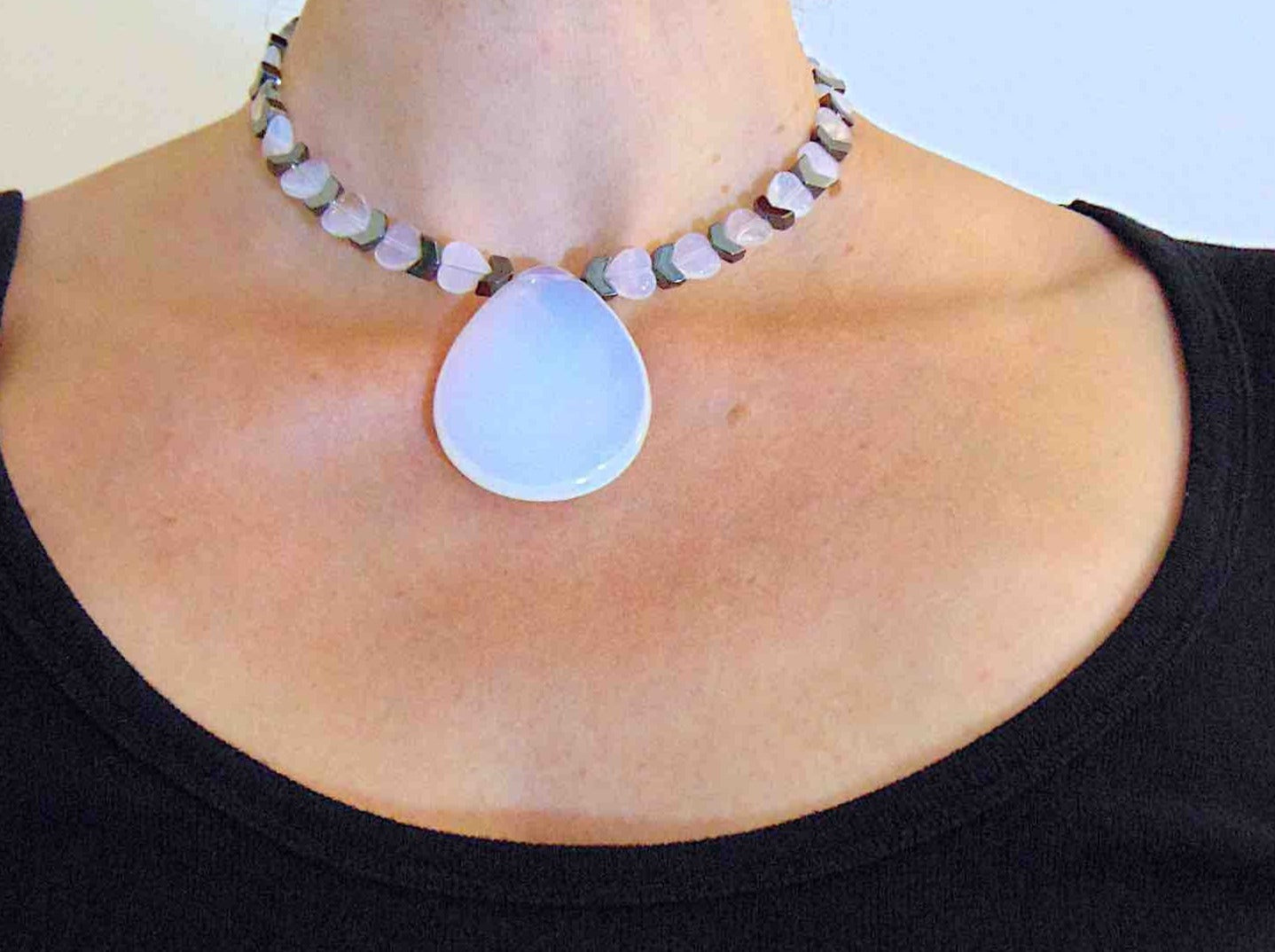 Collier tour de cou avec pendentif goutte 50mm de pierre de lune synthétique (opalite), petits coeurs et chevrons en hématite, fermoir métal