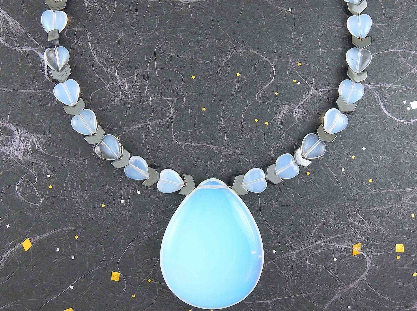 Collier tour de cou avec pendentif goutte 50mm de pierre de lune synthétique (opalite), petits coeurs et chevrons en hématite, fermoir métal