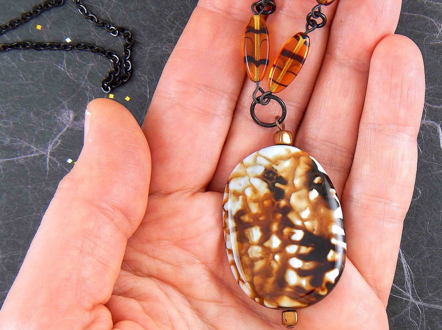 26-inch necklace with speckled black-brown-white jasper stone pendant, striped amber glass beads, black stainless steel chain