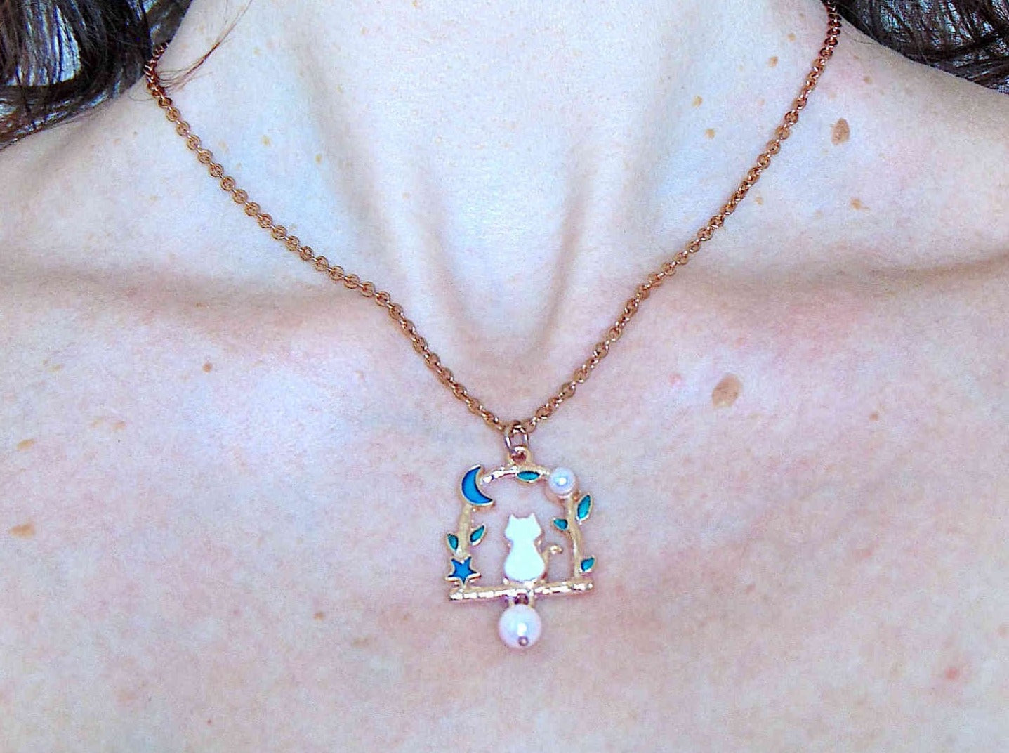 17-inch necklace with tiny enamelled white cat sitting on a branch, blue moon and star, pearl detail, rose gold-toned stainless steel chain