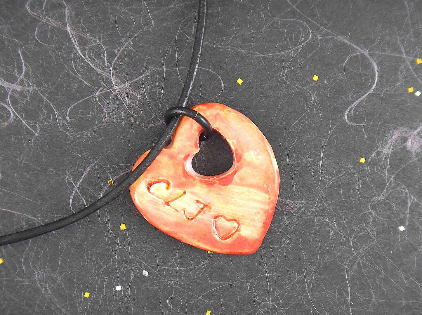 18-inch necklace with marbled red and yellow ceramic heart handmade in Montreal, heart-shaped hole, black leather cord, stainless steel clasp