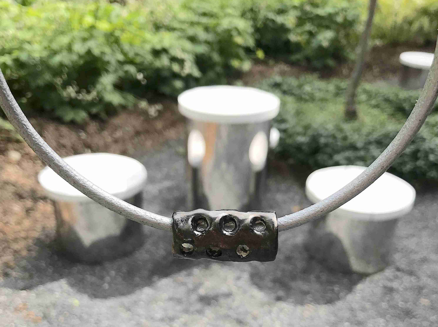 Choker necklace with black nickel ceramic cylinder handmade in Montreal, hole pattern, metallic silver leather cord, stainless steel clasp