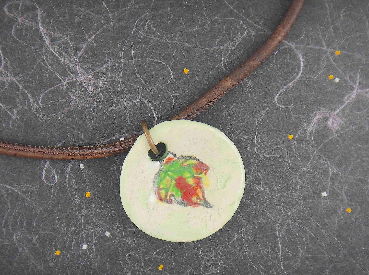 18-inch necklace with off-white ceramic medallion pendant handmade in Montreal, red-green-yellow leaf pattern, chocolate brown cork cord, aluminum ring, stainless steel clasp