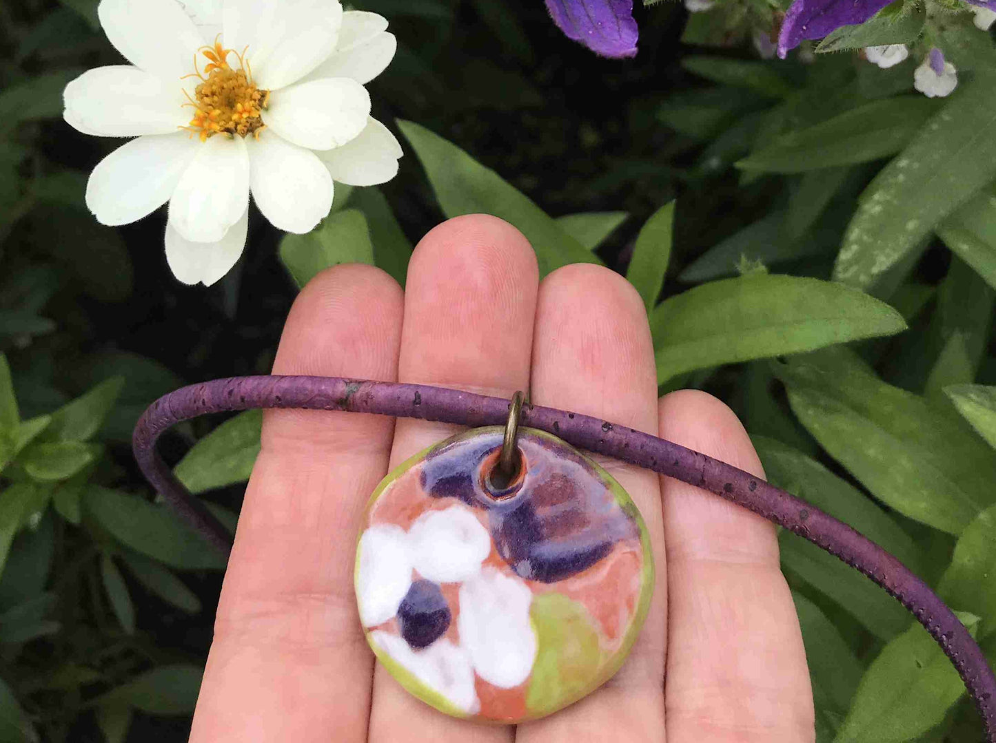 Collier 18 po à pendentif médaillon de faïence terracotta avec motif fleuri blanc-vert-violet fait à la main à Montréal, cordon de liège violet, anneau aluminium, fermoir acier inoxydable