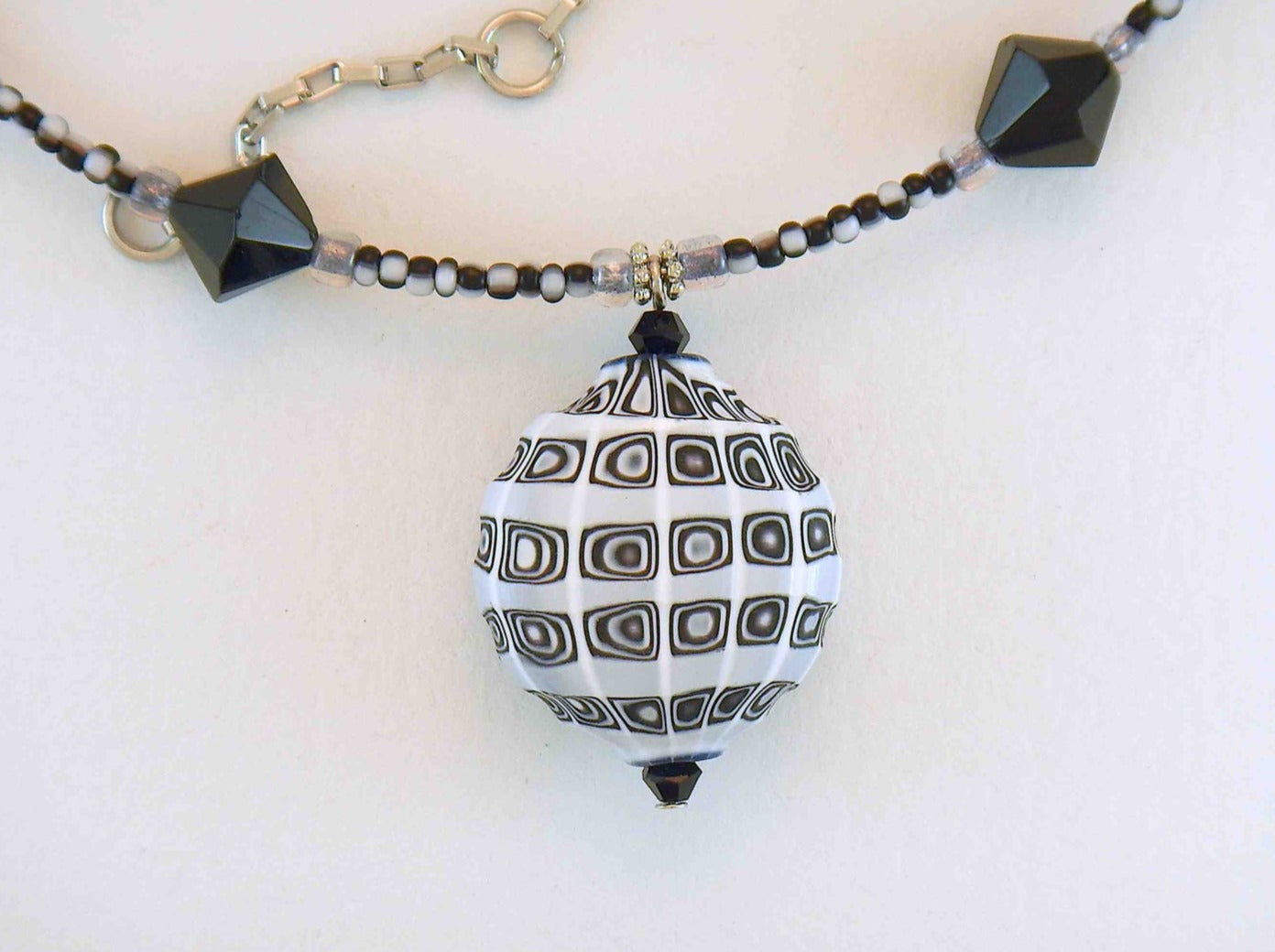14-inch necklace with black & white patterned faceted Murano blown glass pendant, matching Swarovski crystals and glass beads, rectangle-link stainless steel chain