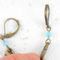 Short earrings with stylized brass fish and bright turquoise Swarovski crystals, brass lever back hooks