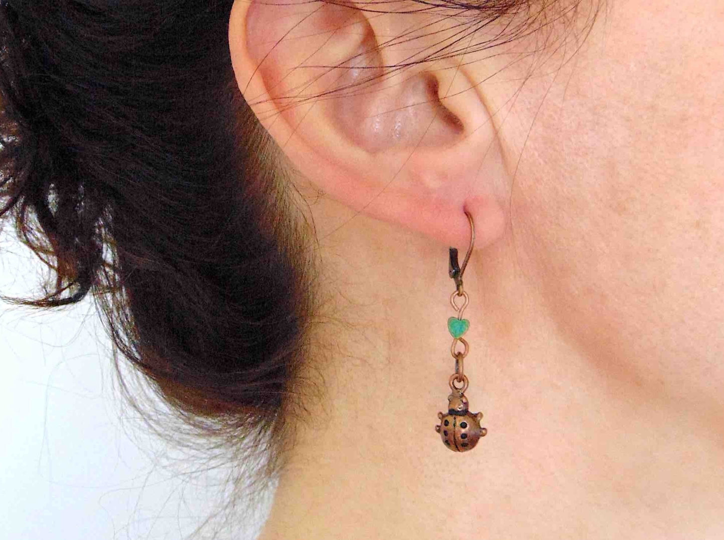 Short earrings with copper ladybugs and tiny iridescent hematite hearts, copper-coloured lever back metal hooks