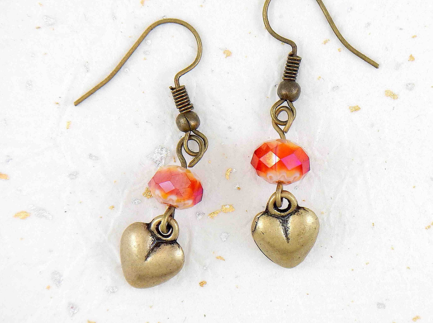 Long earrings with plump brass hearts and iridescent red faceted crystal balls, brass hooks