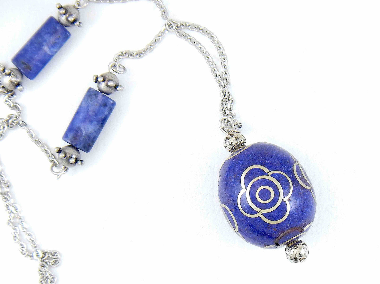 31-inch necklace with deep indigo blue egg-shaped resin Tibetan bead, pewter flower details, sodalite, stainless steel chain