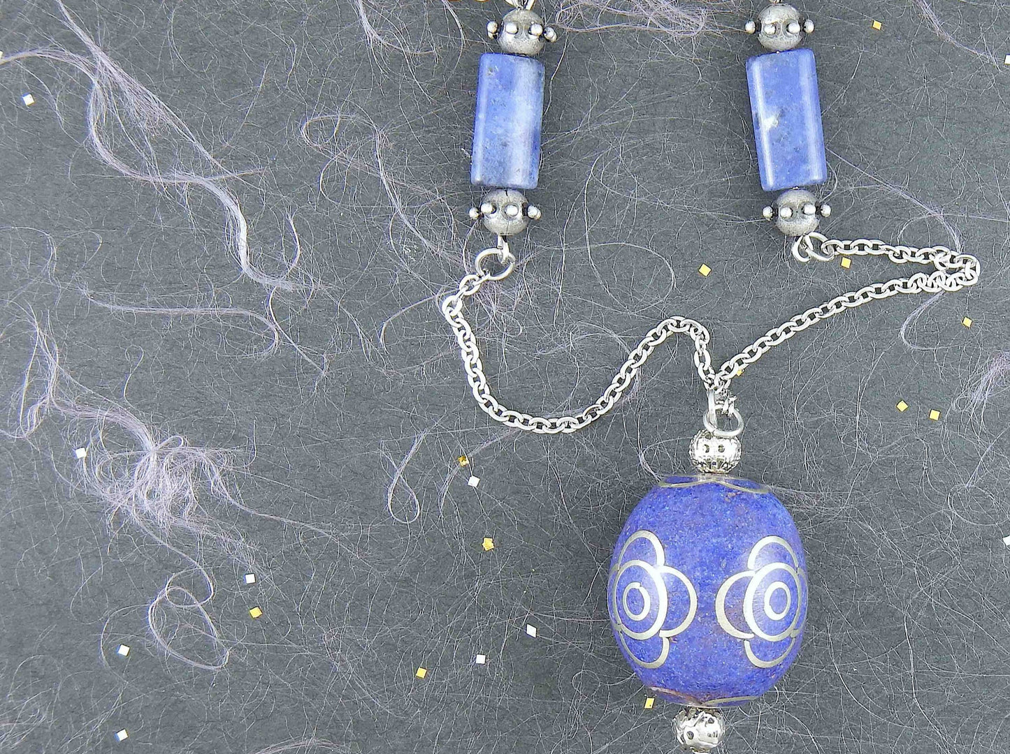 31-inch necklace with deep indigo blue egg-shaped resin Tibetan bead, pewter flower details, sodalite, stainless steel chain