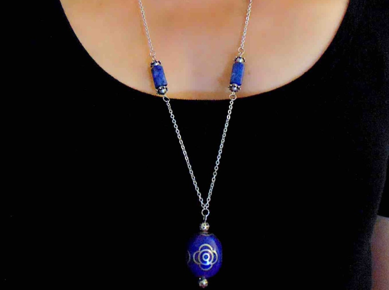 31-inch necklace with deep indigo blue egg-shaped resin Tibetan bead, pewter flower details, sodalite, stainless steel chain