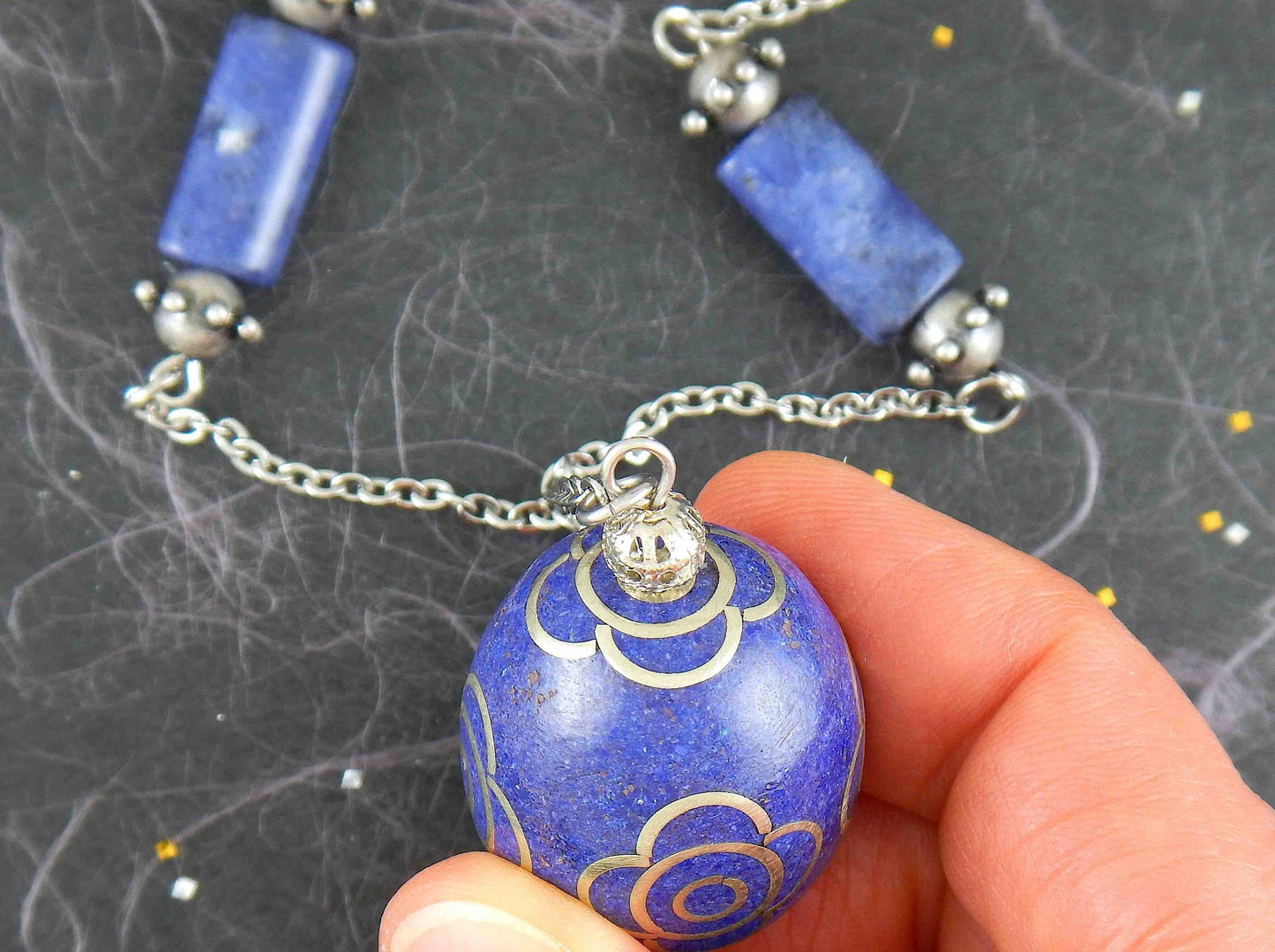 31-inch necklace with deep indigo blue egg-shaped resin Tibetan bead, pewter flower details, sodalite, stainless steel chain