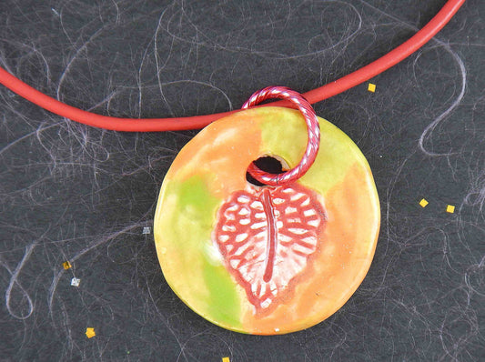 14-inch necklace with red-orange-lime green ceramic medallion handmade in Montreal, leaf pattern, red leather cord, stainless steel clasp