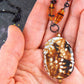 26-inch necklace with speckled black-brown-white jasper stone pendant, striped amber glass beads, black stainless steel chain
