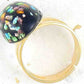 Finger ring with black oval vintage glass cabochon, blue-green-gold speckled, gold-toned stainless steel adjustable base