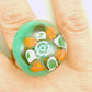 Finger ring with large round emerald green cabochon (Murano style glass handmade in Montreal), orange-white-black flowers, stainless steel adjustable base (US 7-8)