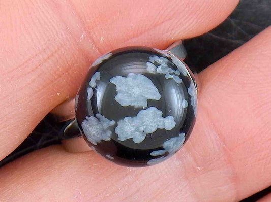 Finger ring with round natural snowflake obsidian stone cabochon, white flakes on black background, stainless steel adjustable base