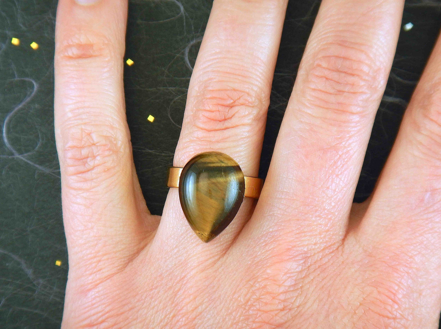 Finger ring with drop-shaped golden tiger eye stone cabochon, gold-toned hypoallergenic stainless steel adjustable base (US 7-8)