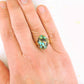 Finger ring with black oval vintage glass cabochon, blue-green-gold speckled, gold-toned stainless steel adjustable base