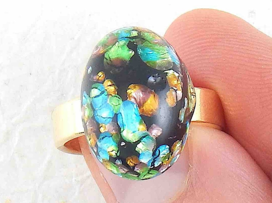 Finger ring with black oval vintage glass cabochon, blue-green-gold speckled, gold-toned stainless steel adjustable base