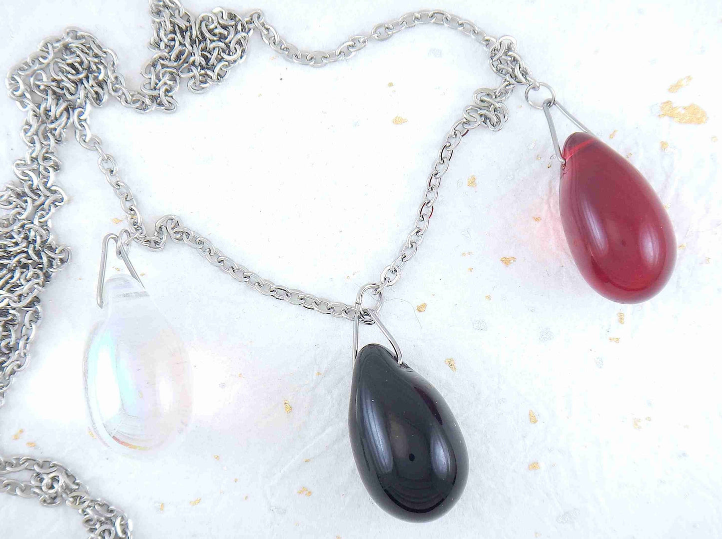 28-inch asymmetrical necklace with 3 glass drops (translucent red, opaque black, iridescent clear), hypoallergenic stainless steel chain